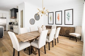 A modern dining area with a wooden table, white upholstered chairs, and a decorative ceiling light. - Luxury Oasis~3.5mi from Scottsdale~Pool~Game Rm (Scottsdale)