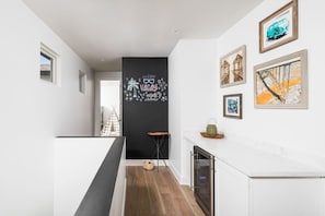 A modern kitchen with white cabinetry, a black accent wall, and a small dining area with a table and chairs. - Luxury Oasis~3.5mi from Scottsdale~Pool~Game Rm (Scottsdale)