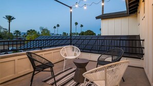Ein Balkon mit zwei Korbstühlen, einem kleinen runden Tisch und Lichterketten.