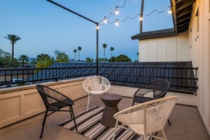 A balcony with two wicker chairs, a small round table, and string lights. - Luxury Oasis~3.5mi from Scottsdale~Pool~Game Rm (Scottsdale)