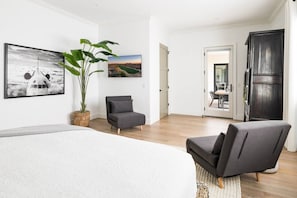 A modern bedroom with a bed, a grey armchair, a large potted plant, and two wall art pieces. - Luxury Oasis~3.5mi from Scottsdale~Pool~Game Rm (Scottsdale)