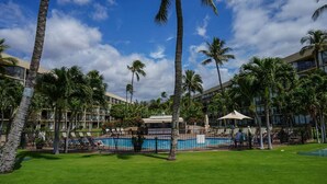 Ein Hotel mit Pool, umgeben von Palmen und blauem Himmel.