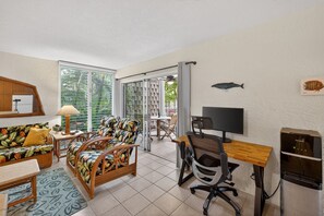 Une pièce comprenant un canapé, un bureau, un ordinateur et un réfrigérateur.