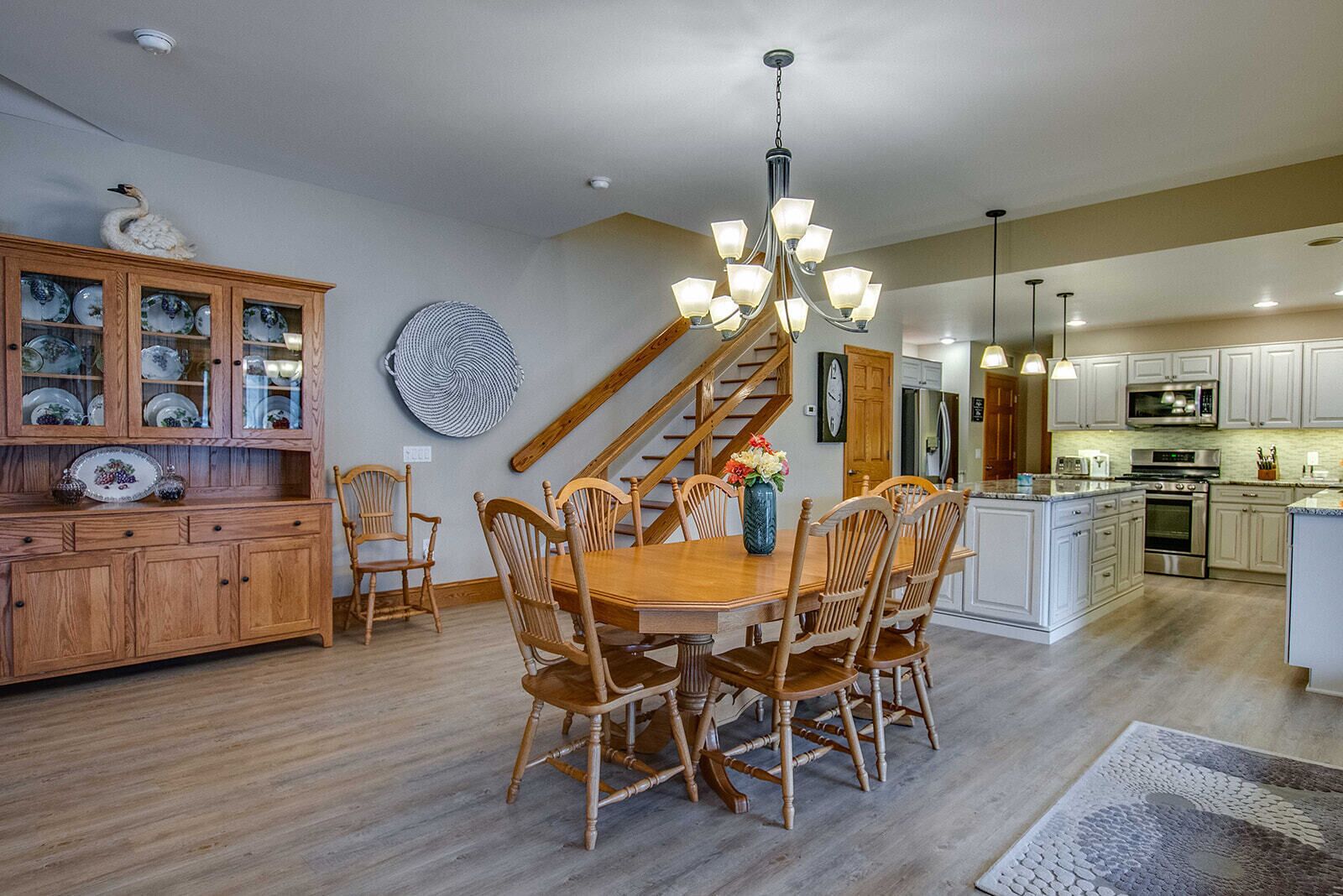 A spacious kitchen with wooden cabinetry, a dining area with a wooden table and chairs, and a staircase leading to another level.