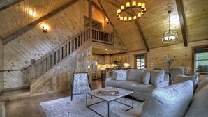 A spacious log cabin interior with a staircase, a living area with sofas, a dining area, and a kitchen. - Luxury Mountain Cabin with Amazing Views and Hot Tub (Dog Friendly) (Blue ridge)