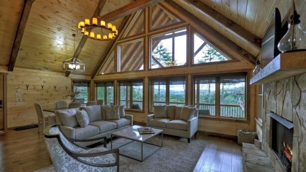 A spacious living room with a high ceiling, large windows, a fireplace, and a cozy seating area. - Luxury Mountain Cabin with Amazing Views and Hot Tub (Dog Friendly) (Blue ridge)