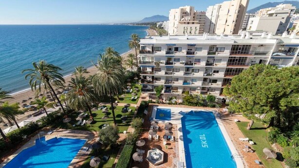 Ein Hotel mit mehreren Schwimmbecken, einem Strand und Meerblick.