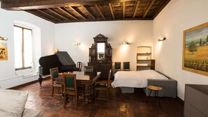 Una habitación con un piano, una cama, un escritorio y un cuadro en la pared.