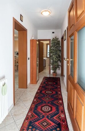 Stylish hallway with a patterned carpet leading to a room, featuring wooden doors and a radiator.