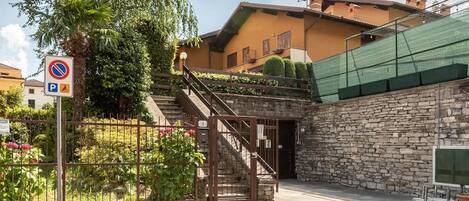 A courtyard with a stone wall, a staircase, and a no parking sign.