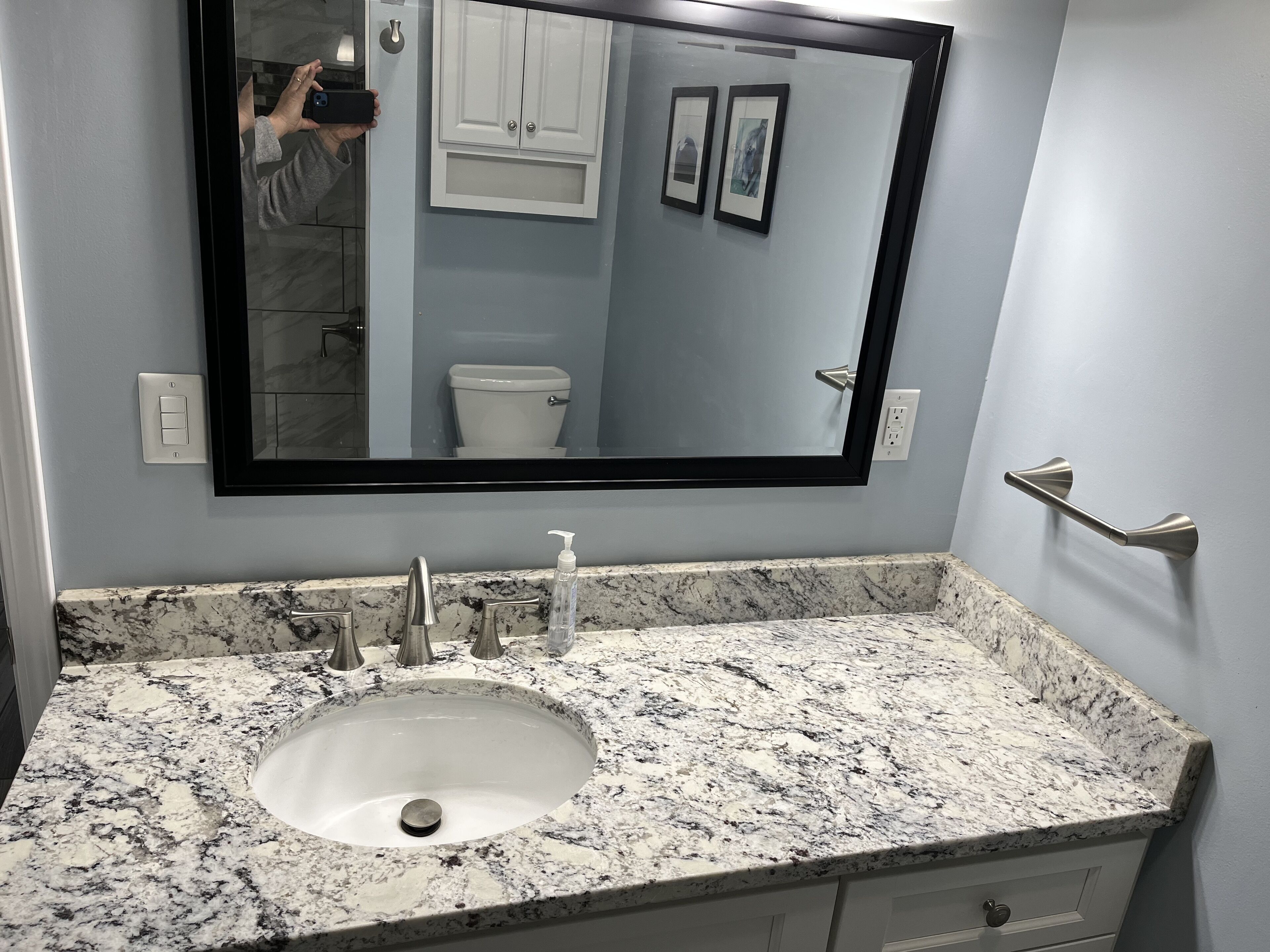 Une salle de bain avec un lavabo en marbre, un grand miroir et des toilettes.