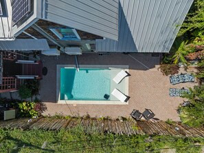 An aerial view of a swimming pool with lounge chairs and a covered patio area.