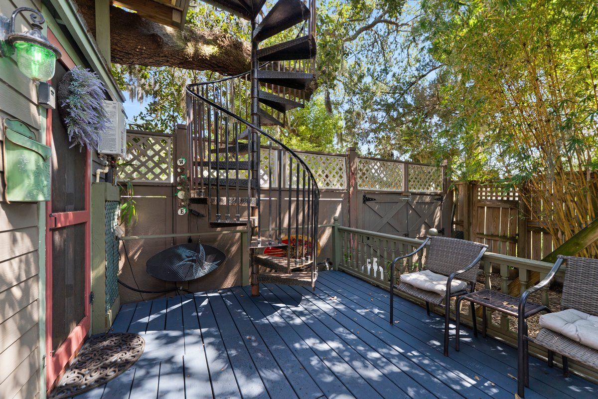 A wooden deck with a spiral staircase, outdoor seating, and a wooden fence.