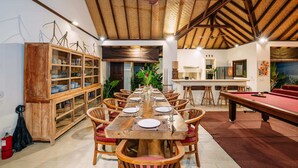 A spacious dining area with a long wooden table set for multiple people, surrounded by wooden chairs. - Villa Cira (Seminyak)