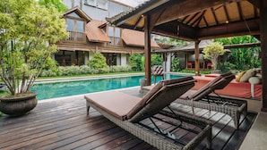 A wooden deck with lounge chairs and a pool. - Villa Cira (Seminyak)
