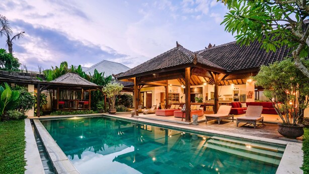 A swimming pool with a covered patio area, a dining space, and lush greenery. - Villa Cira (Seminyak)