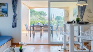 A modern kitchen with a dining area, large windows, and a view of greenery. - Les Coteaux de la Nartelle by Interhome (Sainte Maxime)