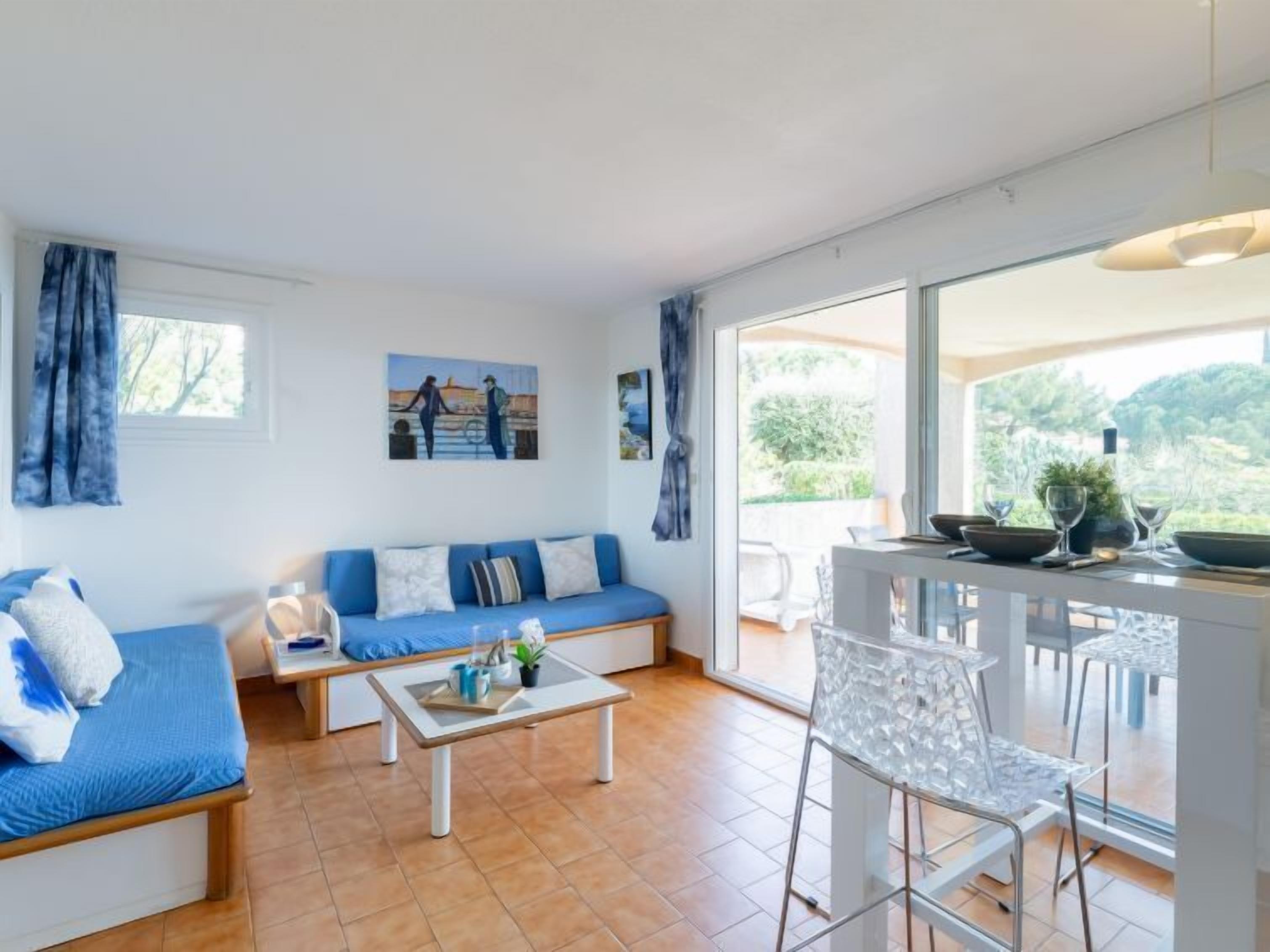 A modern living room with a blue sofa, a coffee table, and a dining area with a glass table and chairs.