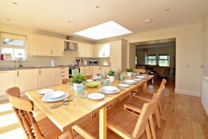 A modern kitchen with a long dining table set for six, wooden chairs, and a skylight above. - HAWTHORN HOUSE - spacious home set amidst lush gardens & rolling countryside (Pathhead)