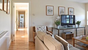 Una sala de estar con un sofá, un televisor y cuadros con vistas de la ciudad en la pared.