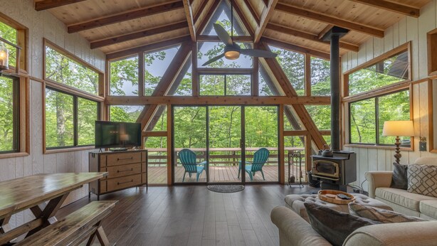 Ein großzügiges Wohnzimmer mit Holzboden, großen Fenstern, einem Kamin und einer gemütlichen Sitzecke.