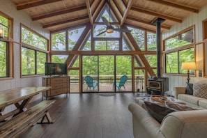 A spacious living room with a wooden ceiling, large windows, a fireplace, and a cozy seating area.