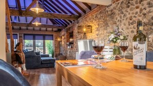 A cozy room with a wooden table, a bottle of wine, and a dog. - Homestead and Black Cat Barn, Southrepps, Norfolk (Southrepps)