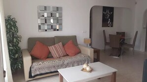 Ein Wohnzimmer mit einer Couch, einem Couchtisch und einem Essbereich mit Tisch und Stühlen.
