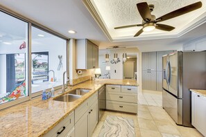 A modern kitchen with granite countertops, stainless steel appliances, and a ceiling fan. - Spacious Punta Gorda Home w/ Private Pool & Views! (Punta Gorda)