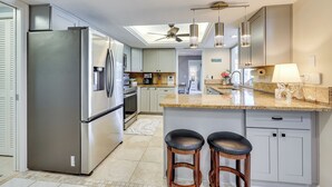 Una cocina moderna con una isla grande, electrodomésticos de acero inoxidable y un tragaluz.