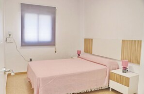 Une chambre à coucher avec un lit, des lampes de chevet, une fenêtre et une table de chevet.