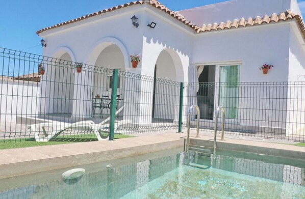 Relax by the pool surrounded by lush greenery and arched doorways.