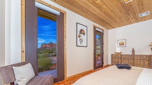 A bedroom with a large bed, a wooden headboard, a window with a view of a mountain, and a framed picture on the wall. - Spacious Ranch House Sedona  (Sedona)