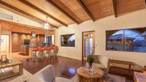 A spacious living area with a wooden ceiling, a kitchen with modern appliances, and large windows offering views of the outdoors. - Spacious Ranch House Sedona  (Sedona)