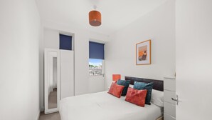 A bedroom with a bed, a wardrobe, a door, and a window.