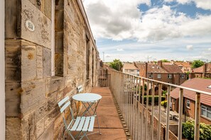 A balcony with a table and chairs, overlooking a residential area with brick houses. - Bright 2‑Bedroom St Andrews Apartment on Pipeland Road with Balcony, Views & Walk to To (St. Andrews)