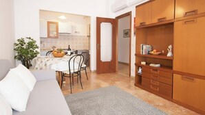 A compact living space with a sofa, a dining table with chairs, and a kitchenette in the background. - Apartment with A/C 250m from beach | Ap19 (Diano Marina)