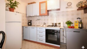 A compact kitchen with white cabinets, a built-in oven, a dishwasher, and a small refrigerator. - Apartment with A/C 250m from beach | Ap19 (Diano Marina)