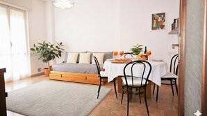 A cozy room with a bed, a dining table with chairs, a potted plant, and a wall art piece. - Apartment with A/C 250m from beach | Ap19 (Diano Marina)