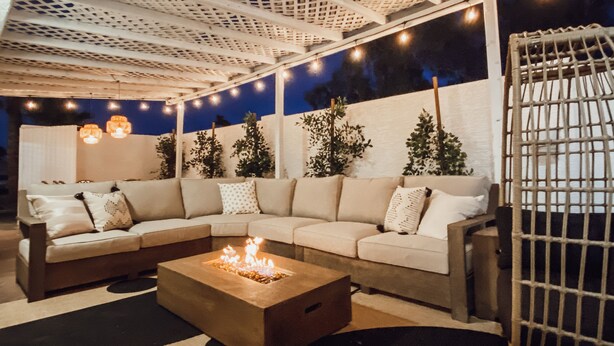 Zona relax all'aperto con divano, boccale e luci decorative.