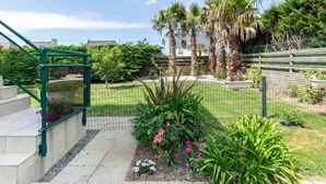 Ein Garten mit Metallzaun, Palmen und verschiedenen Pflanzen.