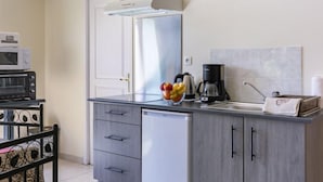Eine kompakte Küche mit Mikrowelle, Kaffeemaschine und Obstschale auf der Arbeitsplatte.