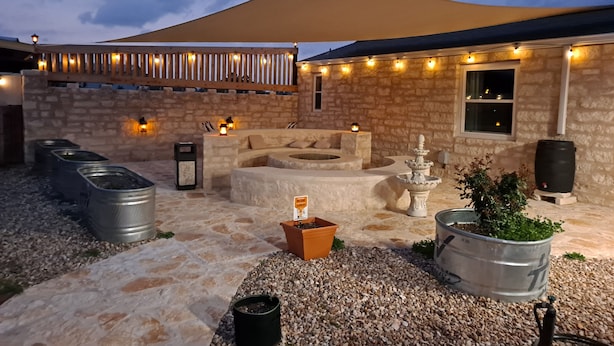 An outdoor seating area with stone walls, a canopy, and string lights.