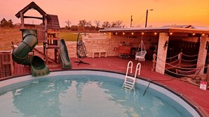 A swimming pool with a slide, a hot tub, and outdoor seating.