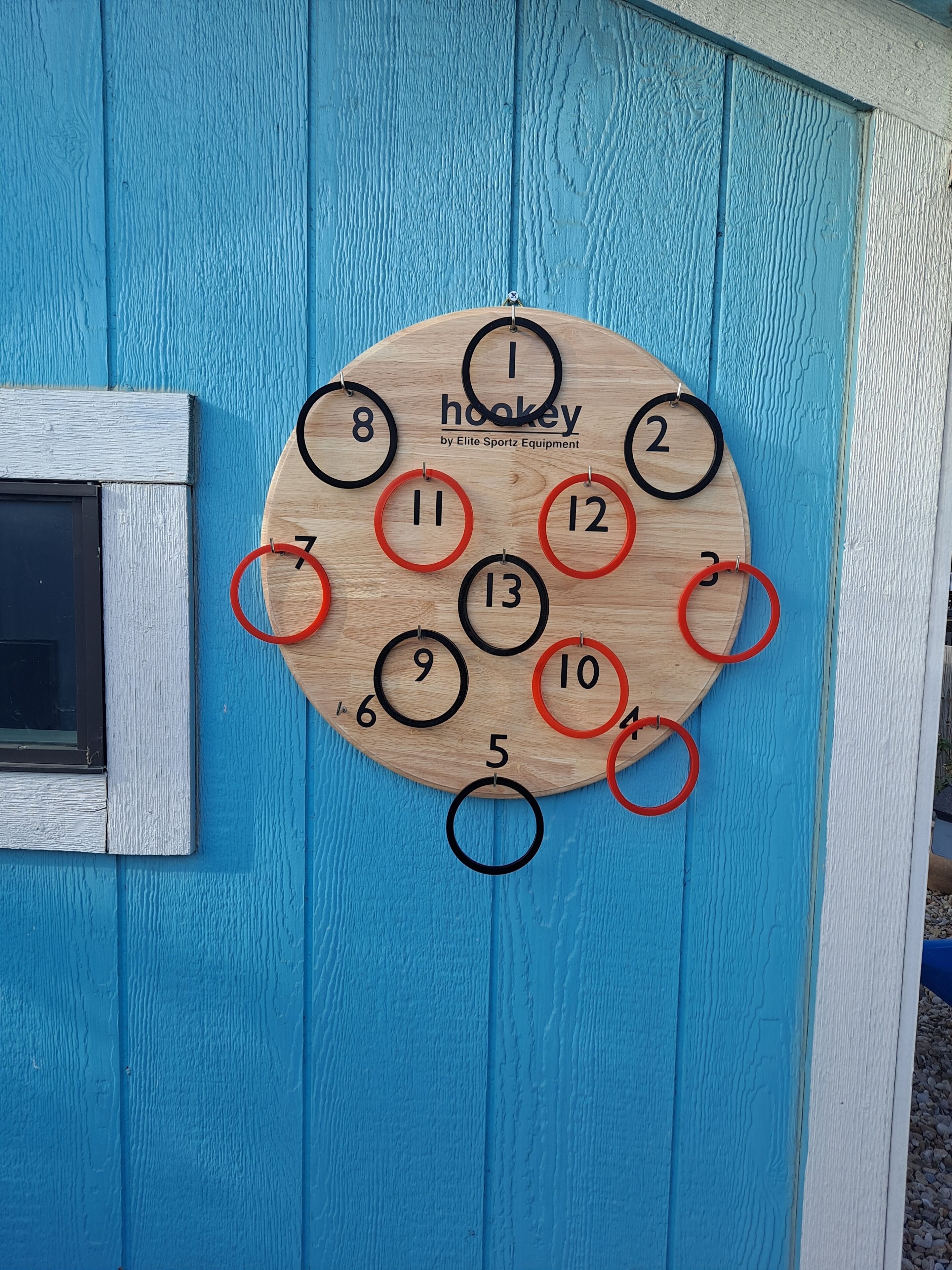 A wooden hockey board with numbered rings against a blue wooden wall.