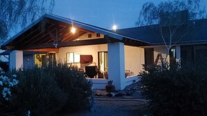 A modern house with a covered porch, a visible window, and a garden area.