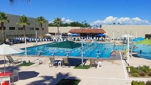 A large outdoor swimming pool with multiple lanes, surrounded by lounge chairs and umbrellas.