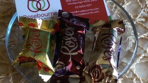 Een glazen schaal gevuld met een assortiment chocolade en een visitekaartje.