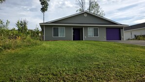 Una casa a due piani con garage integrato, prato curato e cielo sereno.