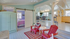 A spacious room with a large bed, a red Adirondack chair, a small table, and a ceiling fan. - Cozy 'Fiddler's Rest:' Cabin: 11 Miles to Skiing! (Vernon)